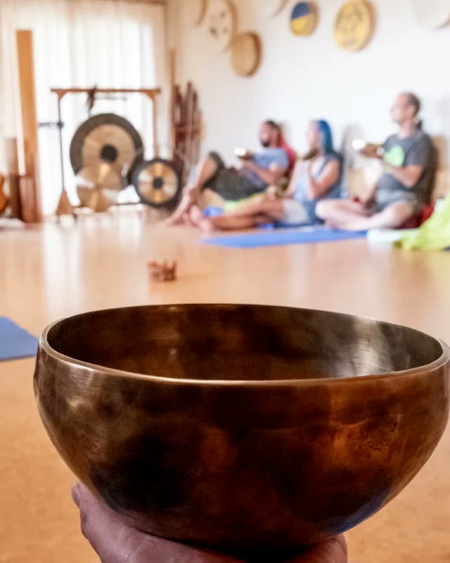 Skupinová zvuková lázeň v Dajáně - tibetská mísa v popředí, účastníci na podložkách a gongy v sále
